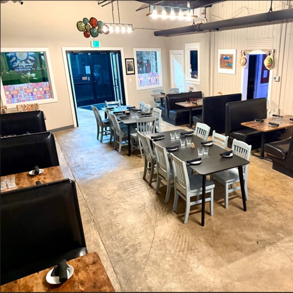 Interior of D Restaurant Latin Cuisine, showing dining tables, chairs, and booths with warm lighting.