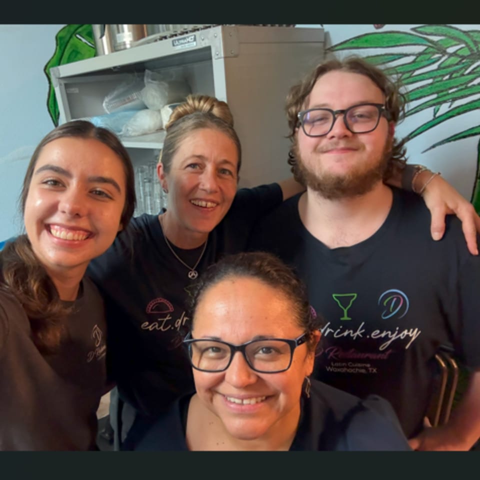 Four smiling D Restaurant staff members, two men and two women, pose for a group photo.